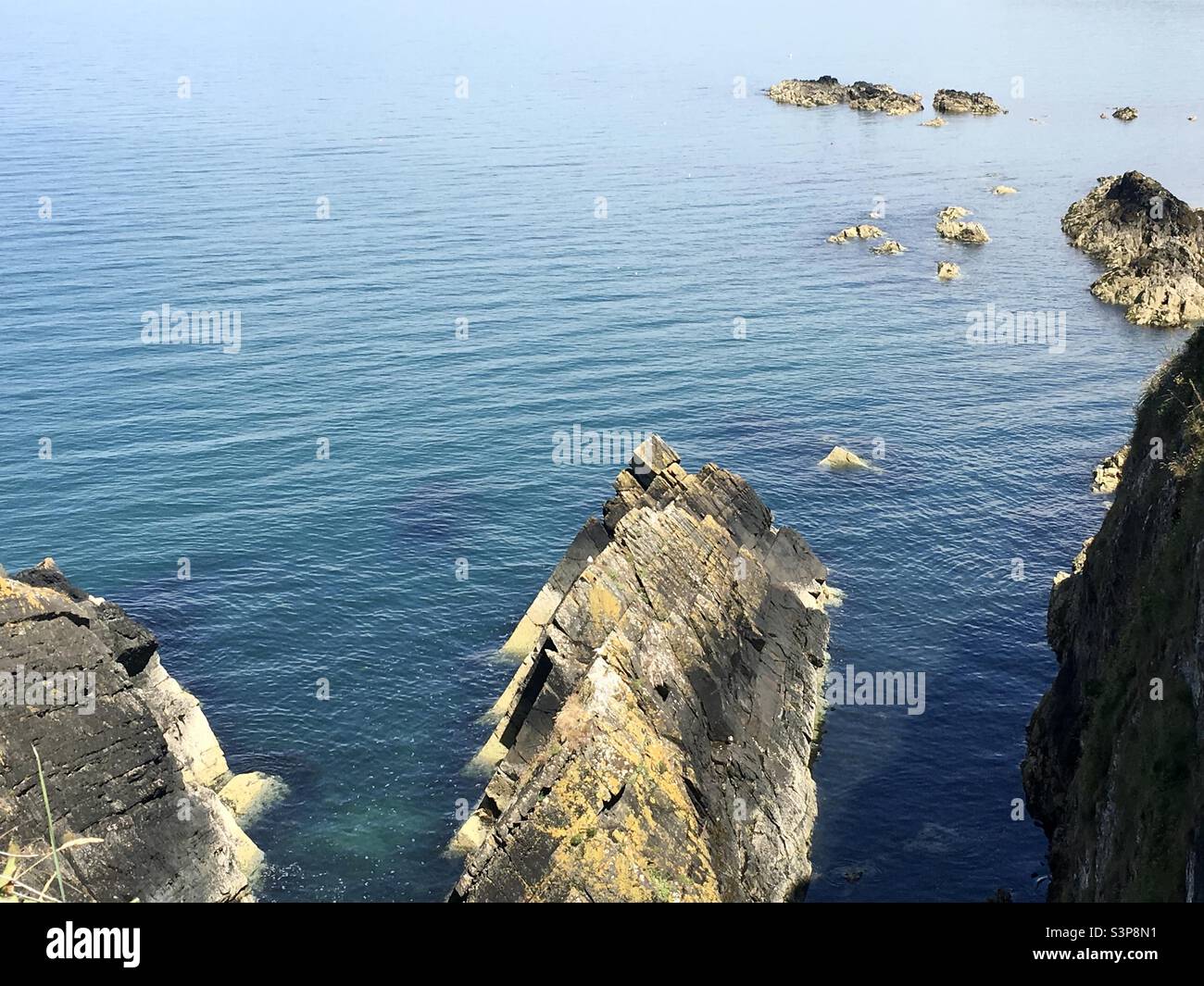 Rocky outcrops and cliffs on coast of blue sea Stock Photo