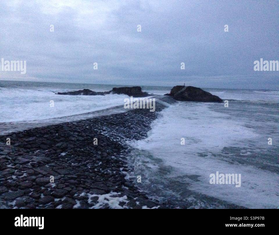 Waves starting to come over Bude breakwater Stock Photo