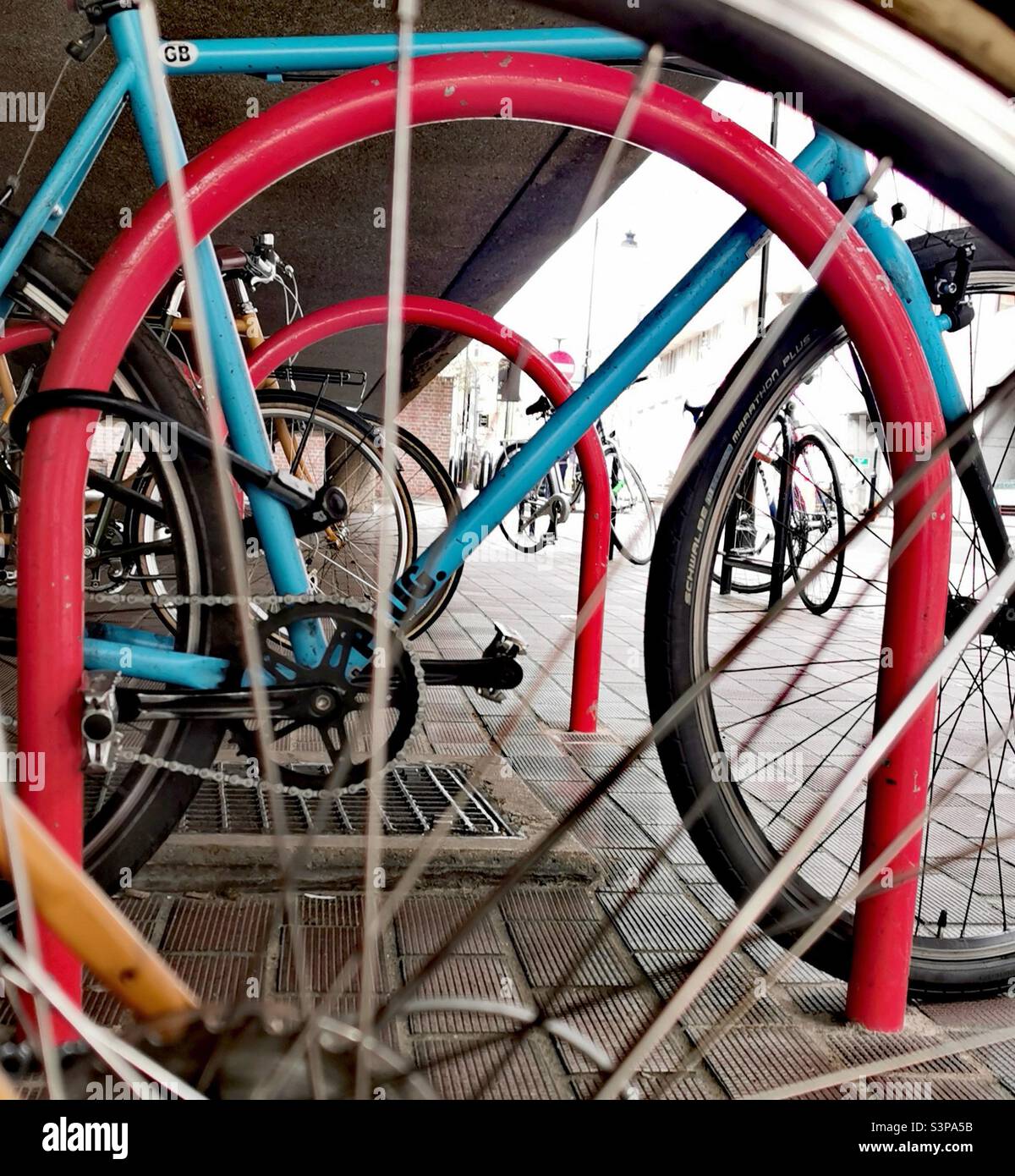 blue bicycle locked to orange bike rack Stock Photo