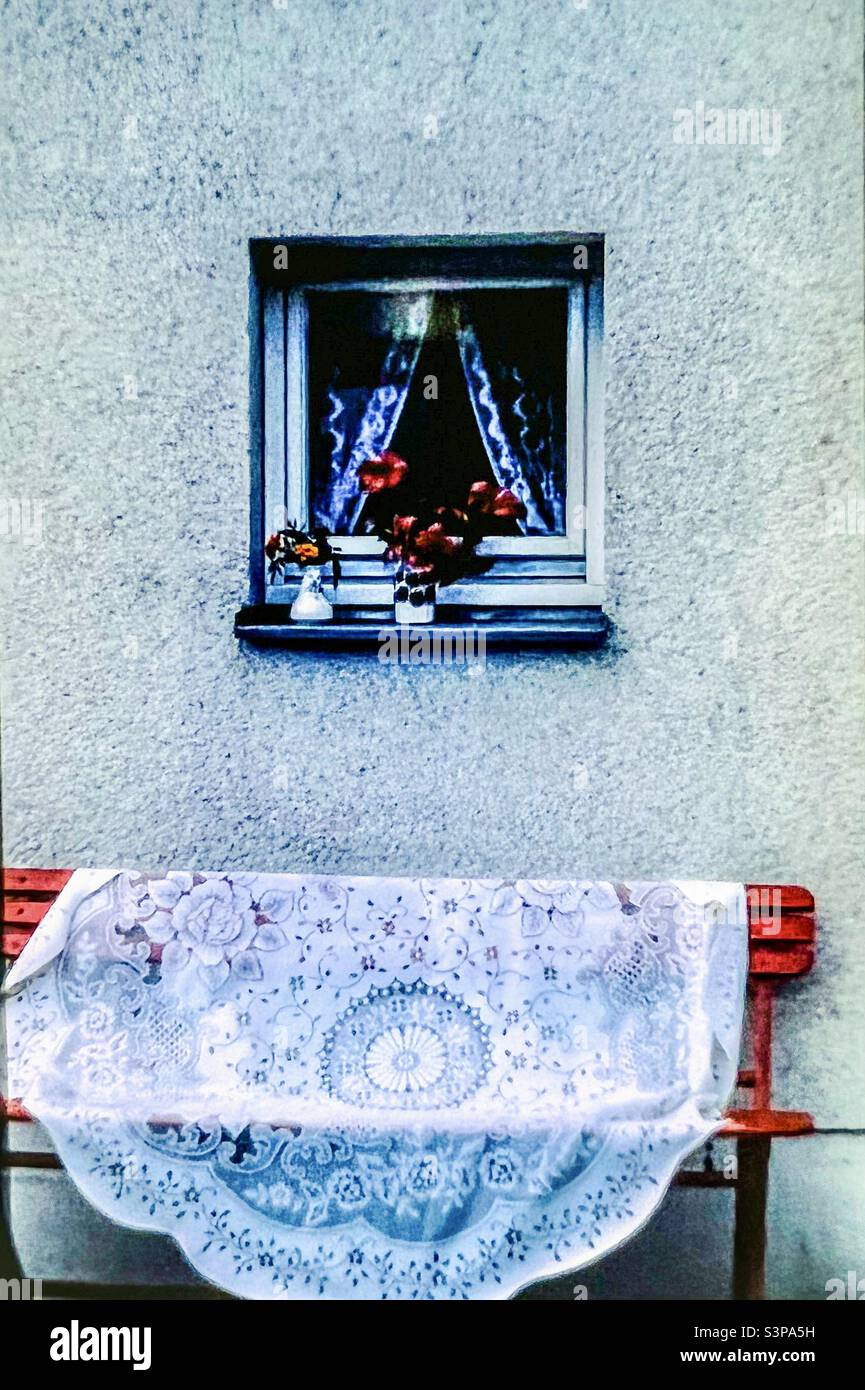 Lace tablecloth on red bench outside Berlin flat Stock Photo