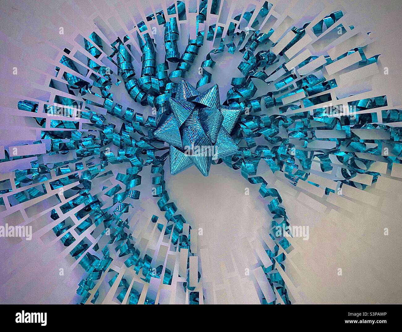 A turquoise gift bow and dangling curled ribbons photographed from above. The IOS app Fragment was used to create the fragmented and abstraction effects. - Smartphone Captured Stock Image
