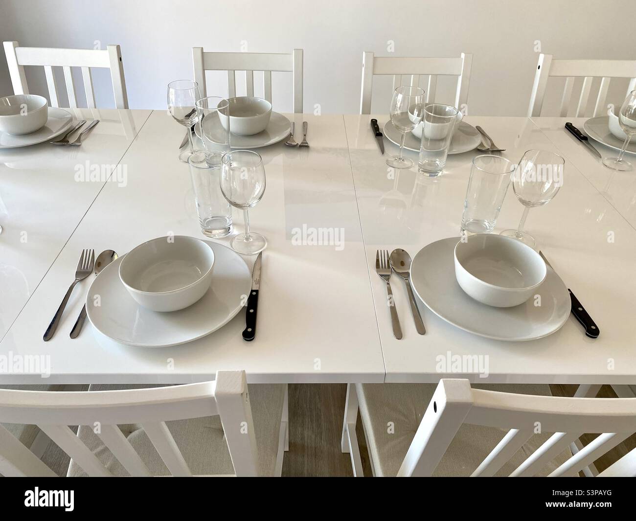Laid table with several place settingswhite furniture Stock Photo