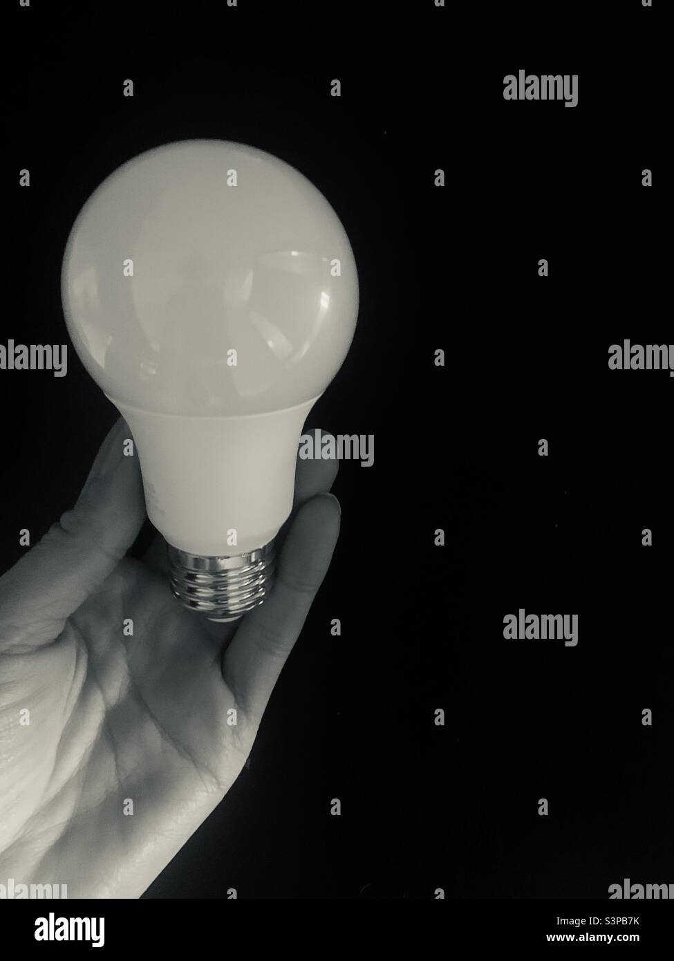 Holding a lightbulb in hand on a black background Stock Photo