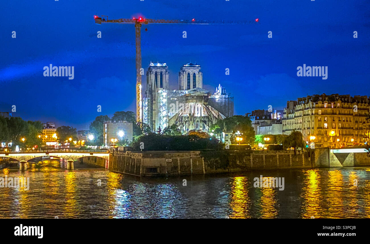 The historic Notre Dame Cathedral under repair at the banks of the Siene River at night. Paris, France - Smartphone Captured Stock Image