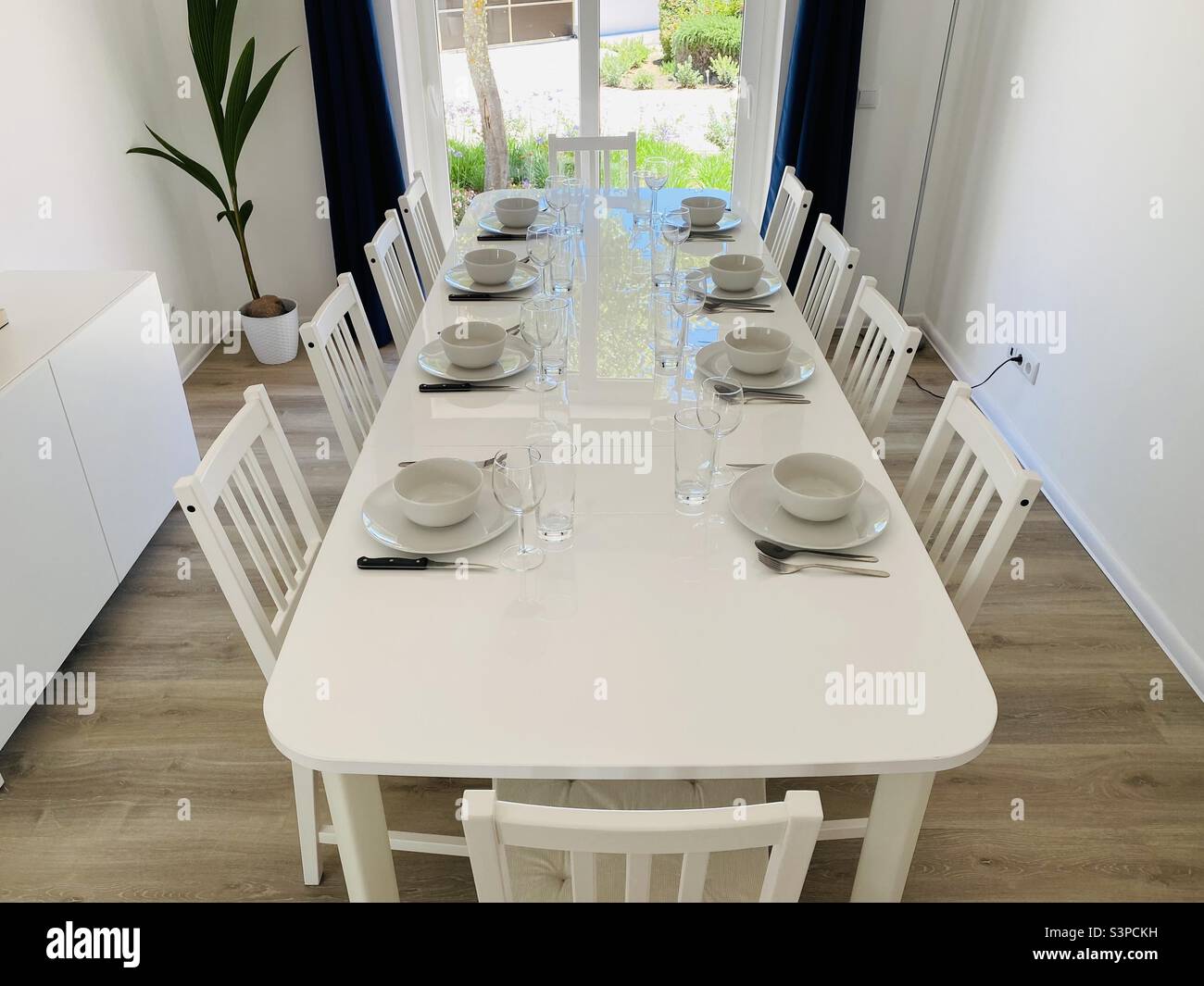 Dining room with white furniture and laid table Stock Photo