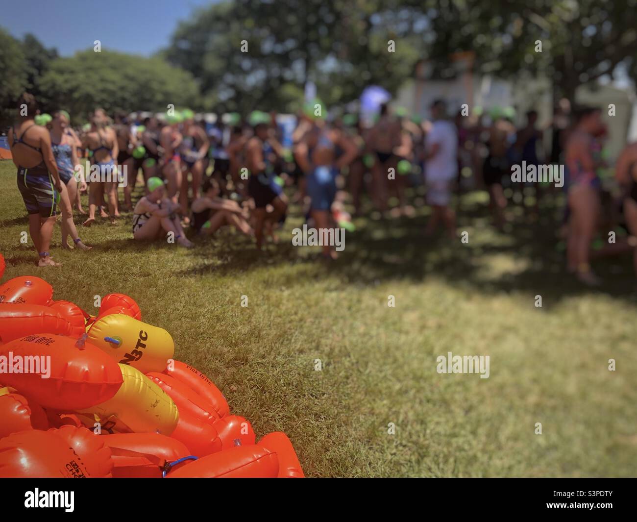 Female swimmers waiting to swim in the annual Midmar Mile 2022 with orange safe-swimmer buoy’s in the foreground - Smartphone Captured Stock Image