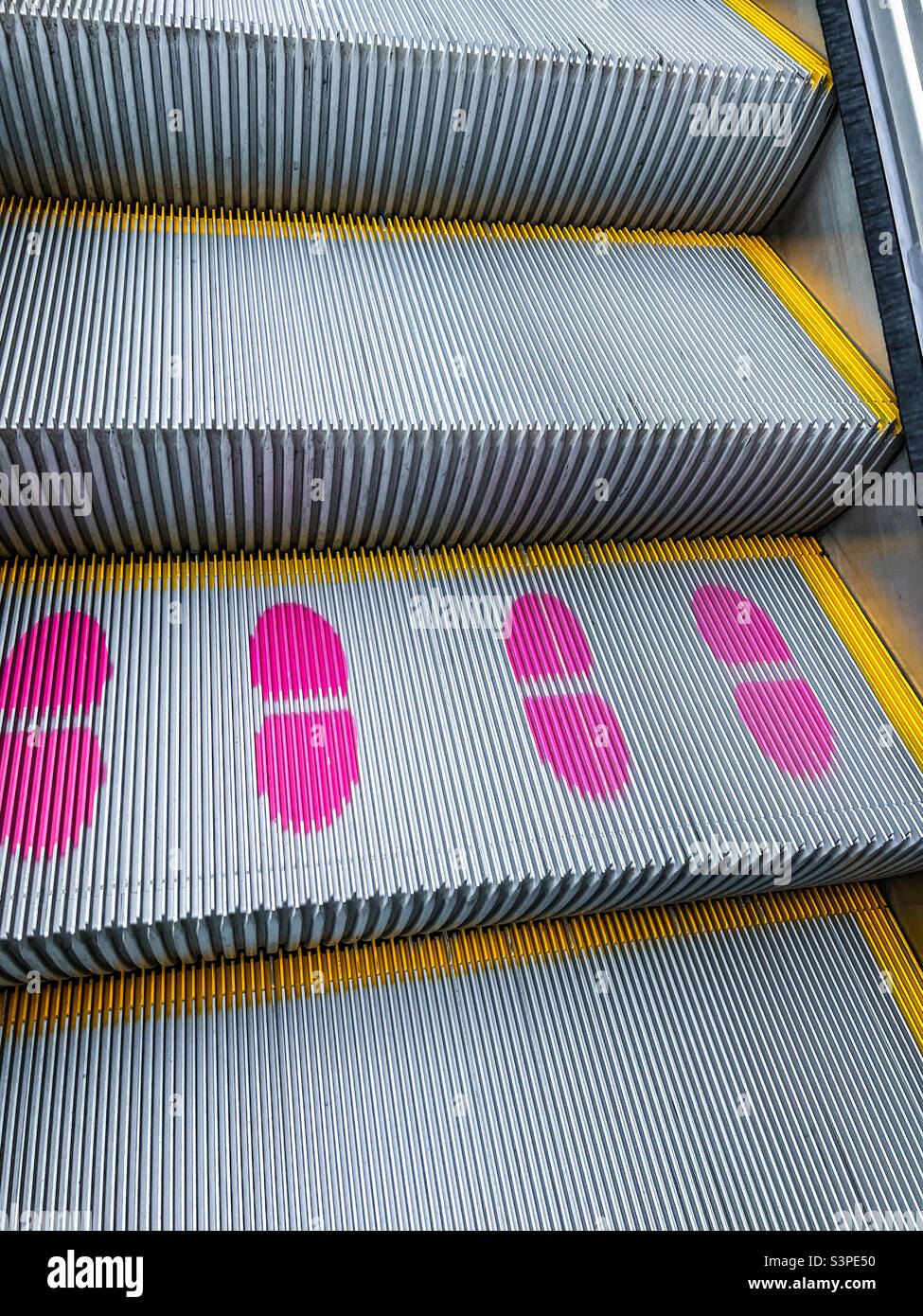 Pink footprints on escalator steps Stock Photo