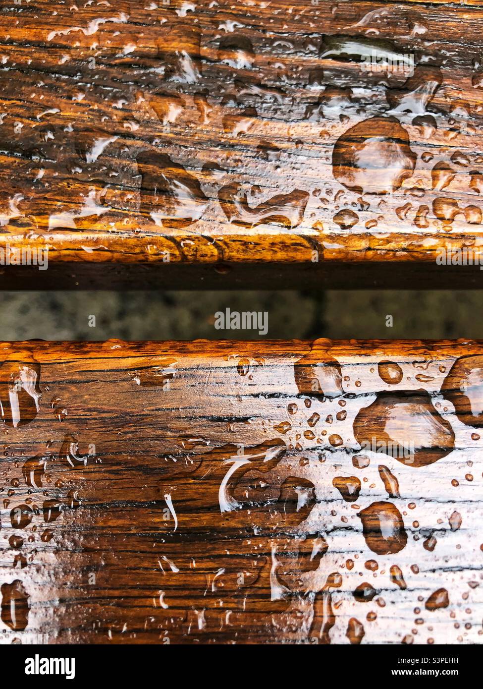 Outdoor wooden bench covered in raindrops - Smartphone Captured Stock Image