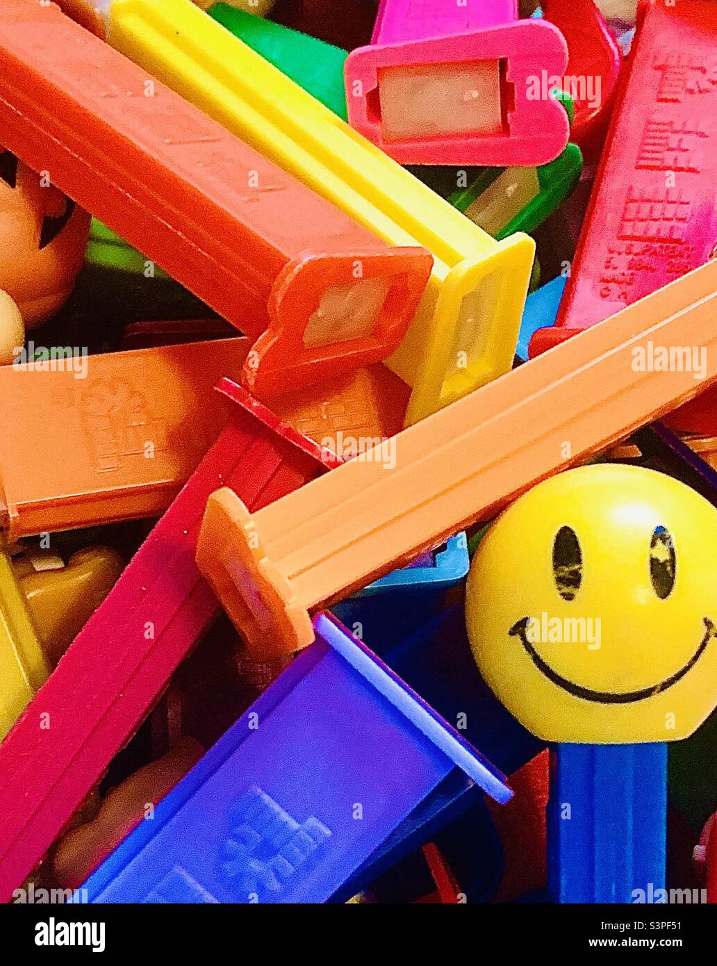 Colorful collection of Pez Dispensers with yellow smiling face Pez Dispenser in lower right corner Stock Photo