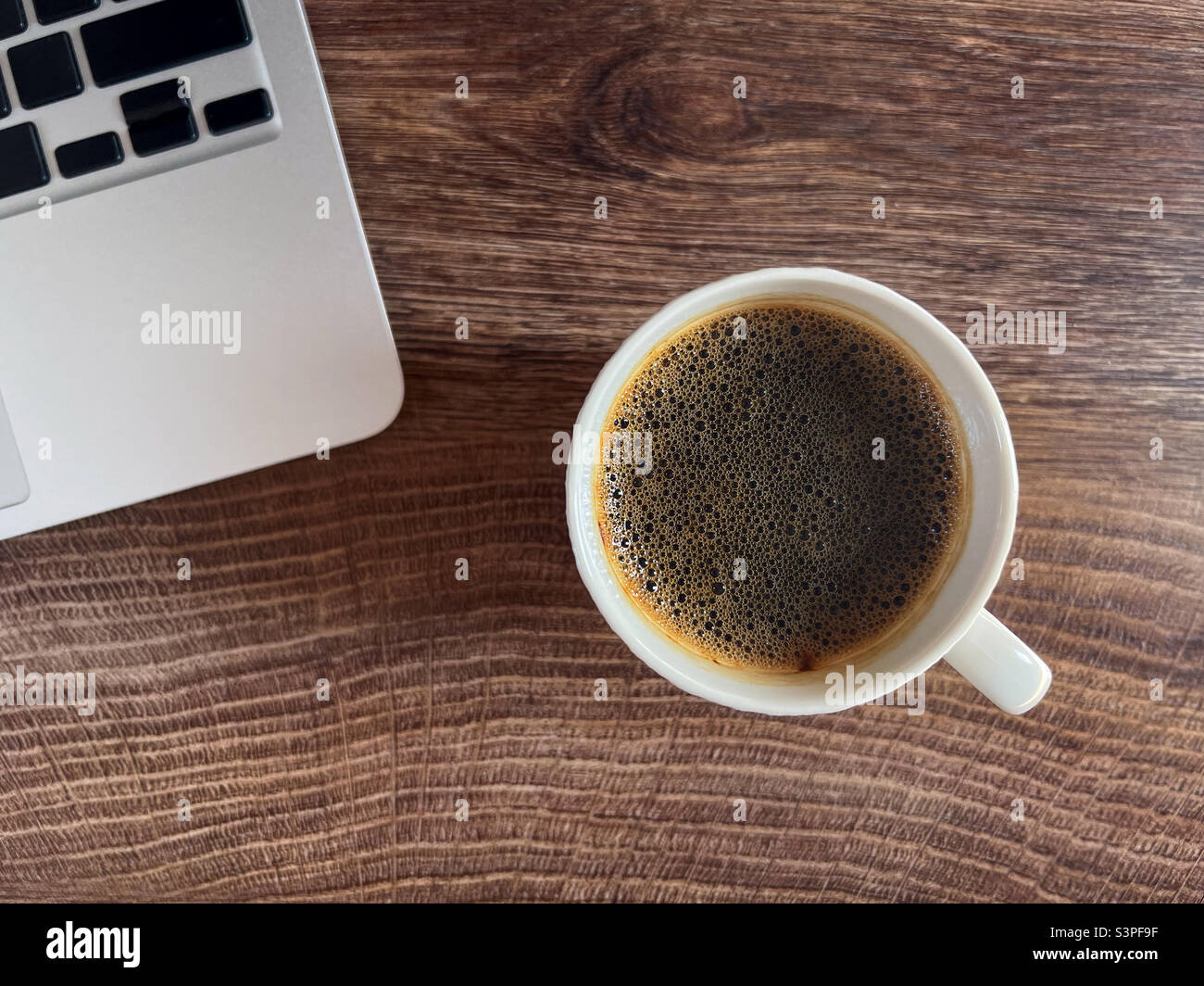 Coffee cup and laptop computer on office desk, top view - Smartphone Captured Stock Image