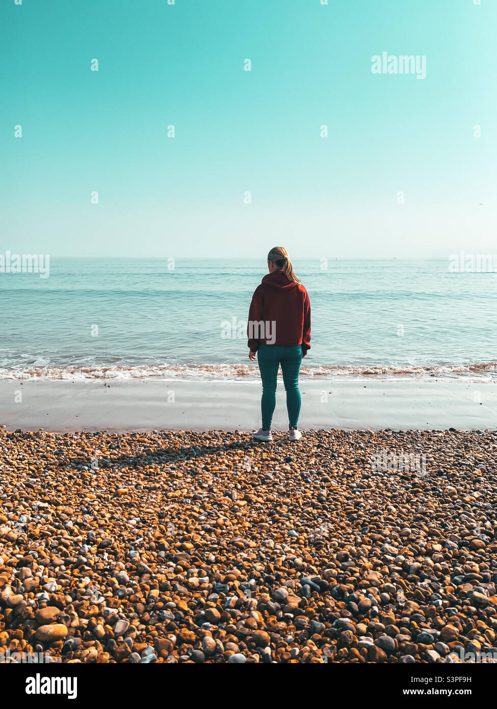 Woman looking out to sea at sunset - Smartphone Captured Stock Image