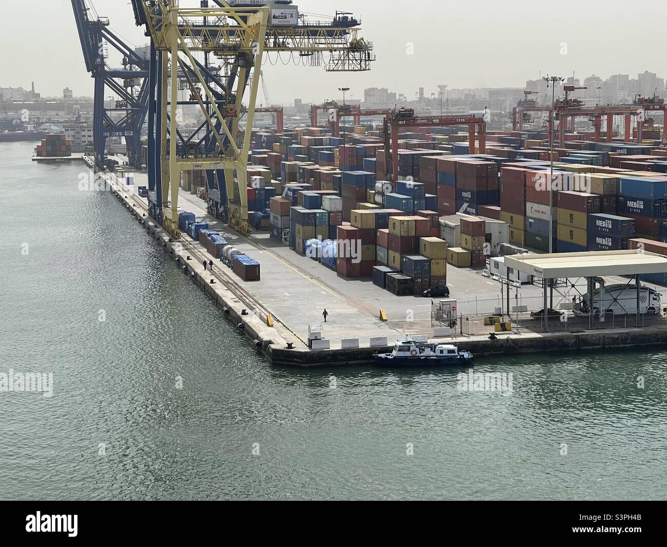 Container Terminal in Alexandria,Egypt equipped with gantry cranes and stowed by containers from different shippers awaiting vessel for cargo operation during sunny spring weather. Stock Photo