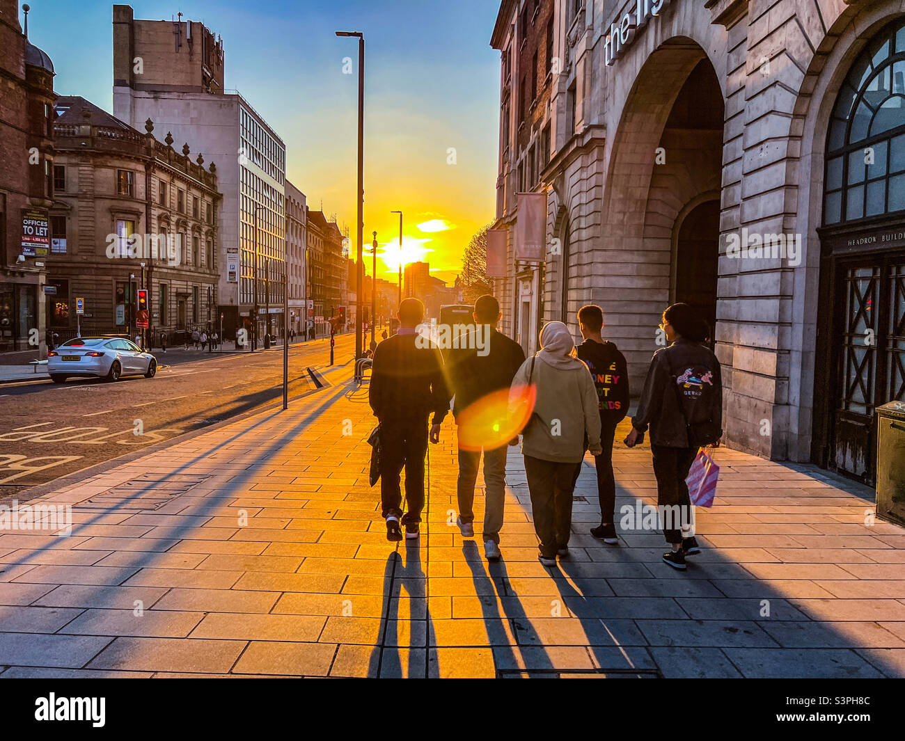 Five friends walking down the Headrow in Leeds city centre with sun setting - Smartphone Captured Stock Image