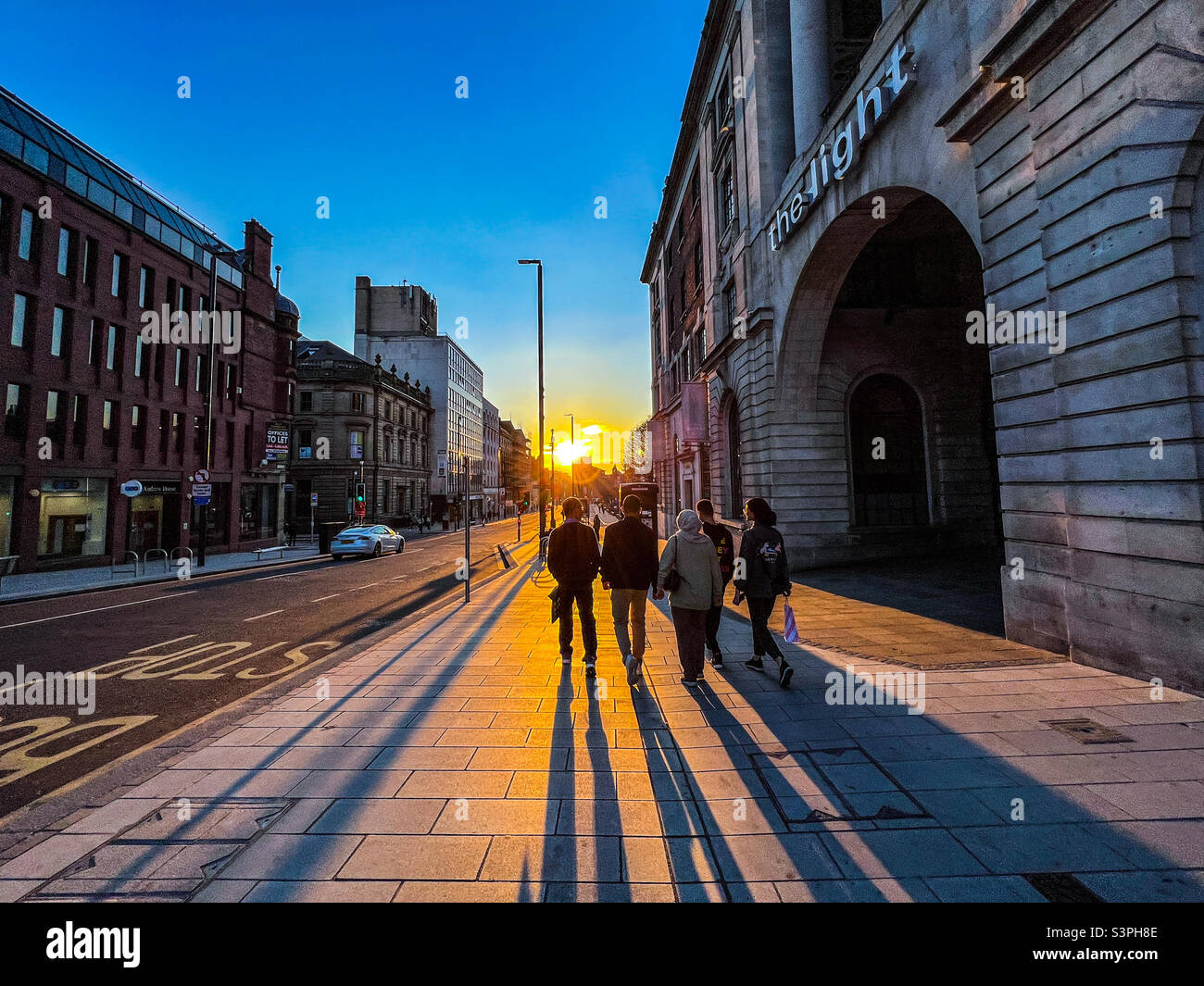 Five friends walking down the Headrow in Leeds city centre with the sun setting Stock Photo