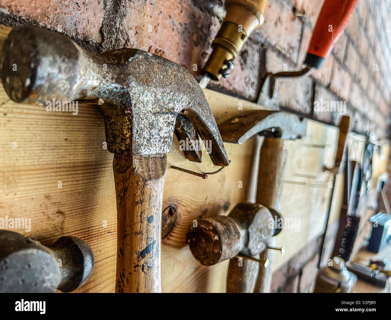 Tools including claw hammers hung on wall Stock Photo