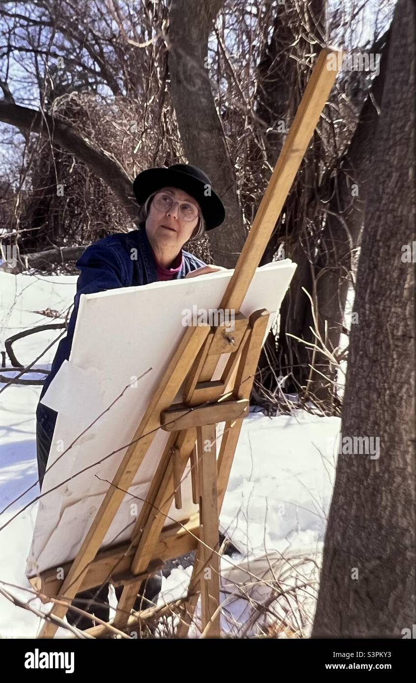 Woman Landscape Painter outside with easel on snowy New England day Massachusetts Stock Photo
