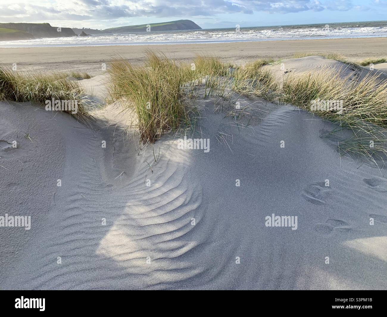 Ripples in Sand dunes with beach sea and headland behind Stock Photo