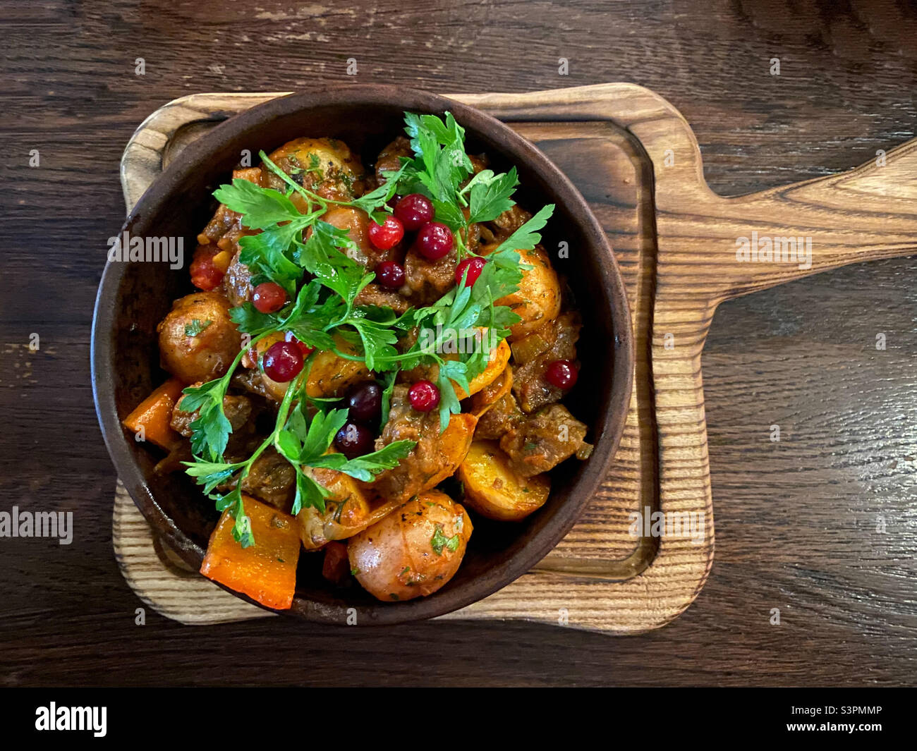 Ojahuri with veal in a brown plate is served on a plate and stands on a wooden table - Smartphone Captured Stock Image