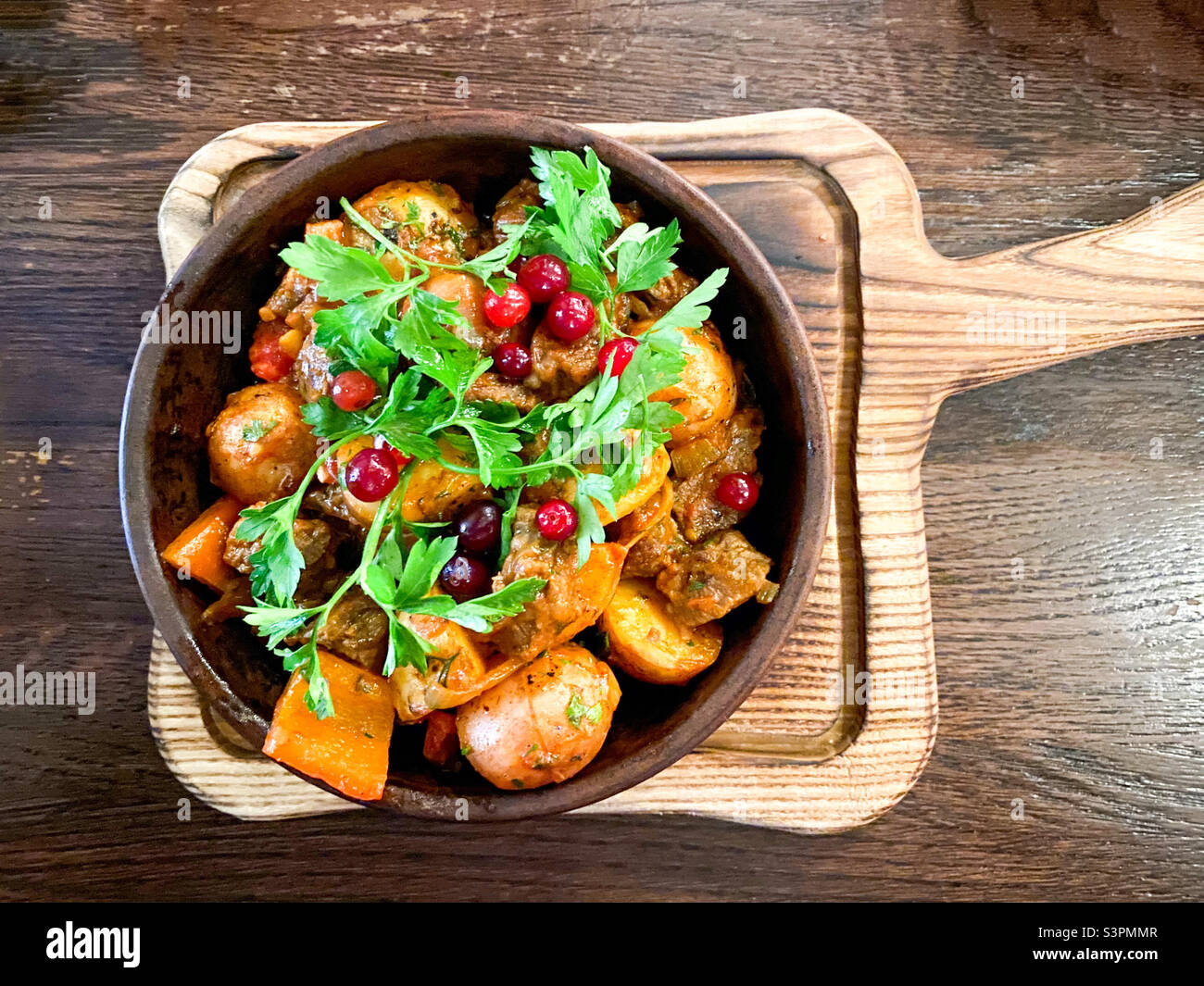 Ojakhuri with veal in a brown plate is served on a plate and stands on a wooden table - Smartphone Captured Stock Image