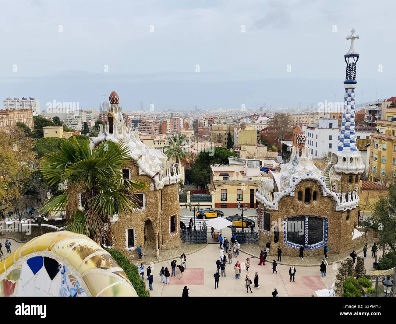 View of the mushroom house and gatehouse at the enterance of Parc Güell, Barcelona, Catalunya, Spain, Europe, from the plaza, by the serpent bench (part of which can be seen in the photo). March 2022. - Smartphone Captured Stock Image