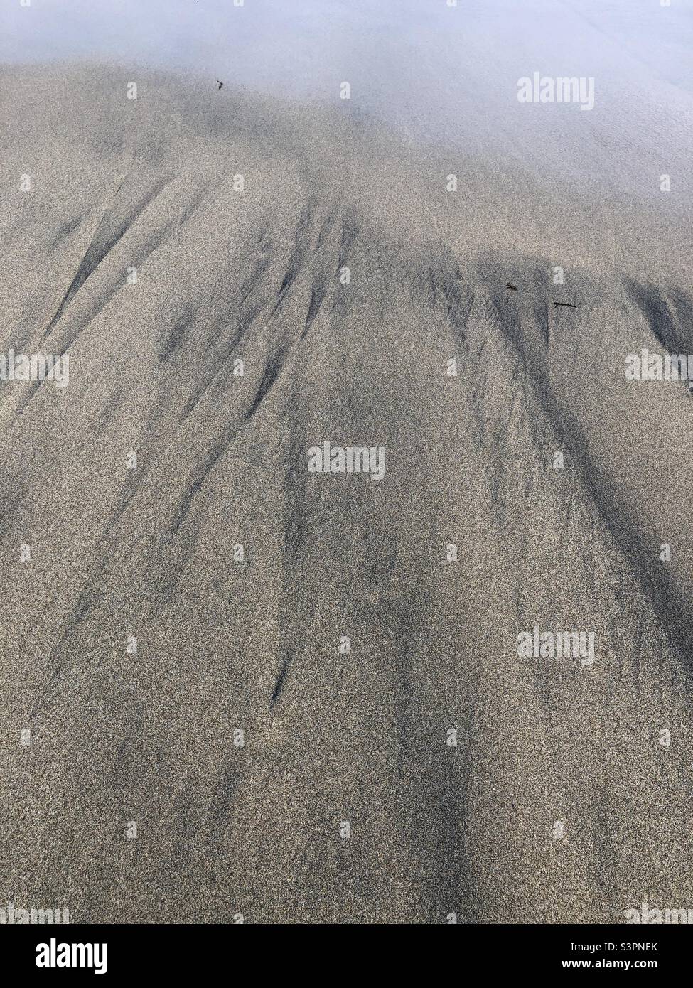 Black streaks of sand and water on a beach in Scotland, United Kingdom - Smartphone Captured Stock Image