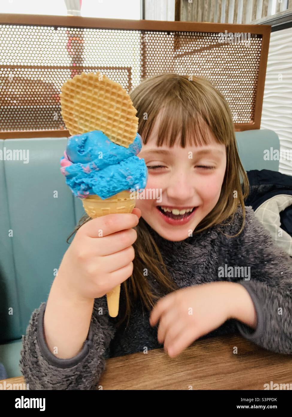 Girl laughing and eating an Unicorn flavoured ice cream cone - Smartphone Captured Stock Image