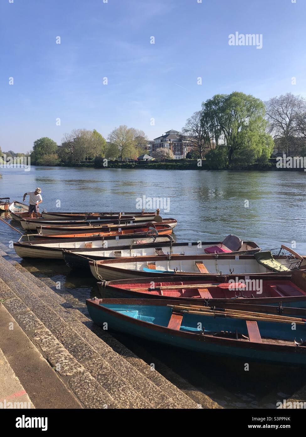 Man arranging boats that are for hire on the river Thames in London Uk - Smartphone Captured Stock Image