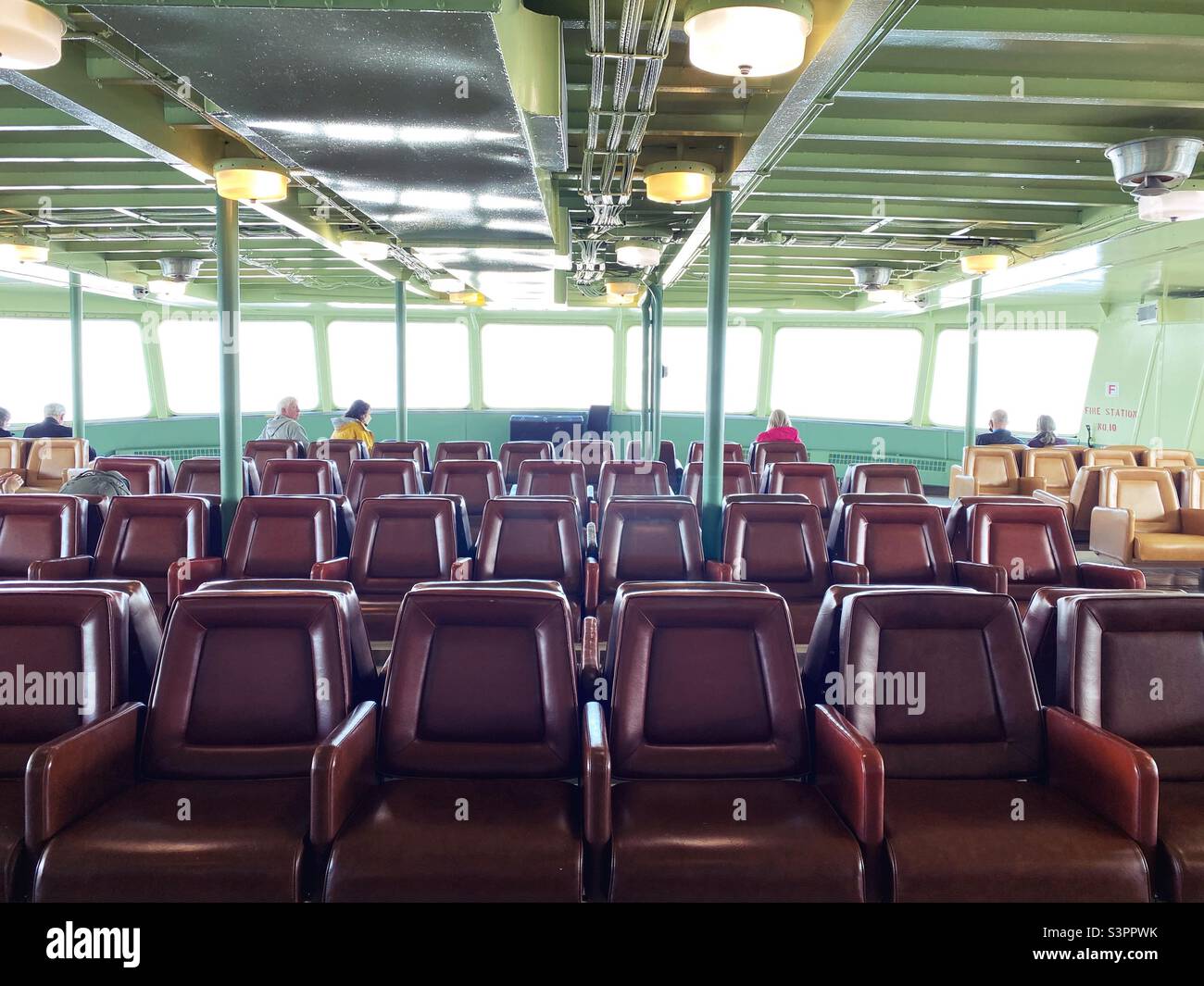 Seats on the observation deck of a ferry, with only a few people on board. Stock Photo