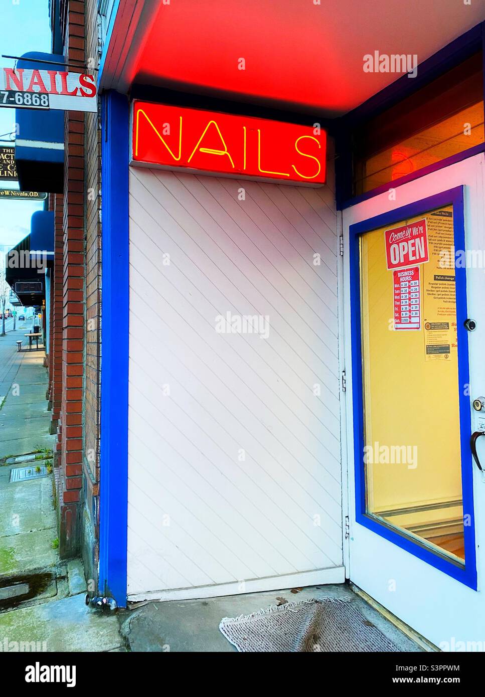 A neon sign in front of a nail salon. Stock Photo