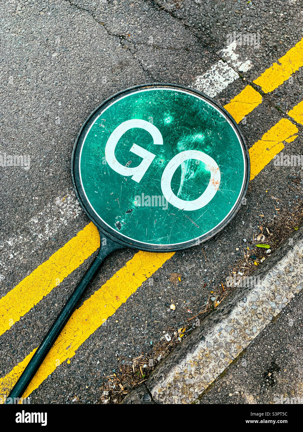 Hand held traffic control sign laying on the road - Smartphone Captured Stock Image
