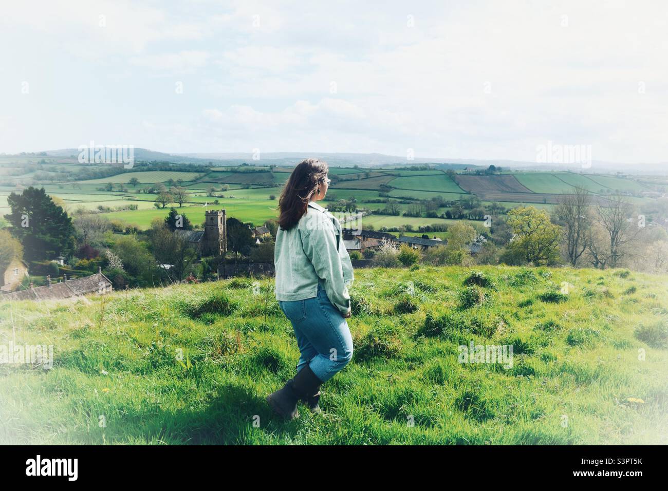 Woman walking on hillside overlooking typical English countryside in Spring Stock Photo
