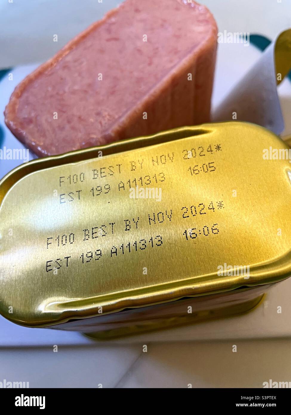 A loaf of Spam next to a tin showing the expiration date, 2022, USA