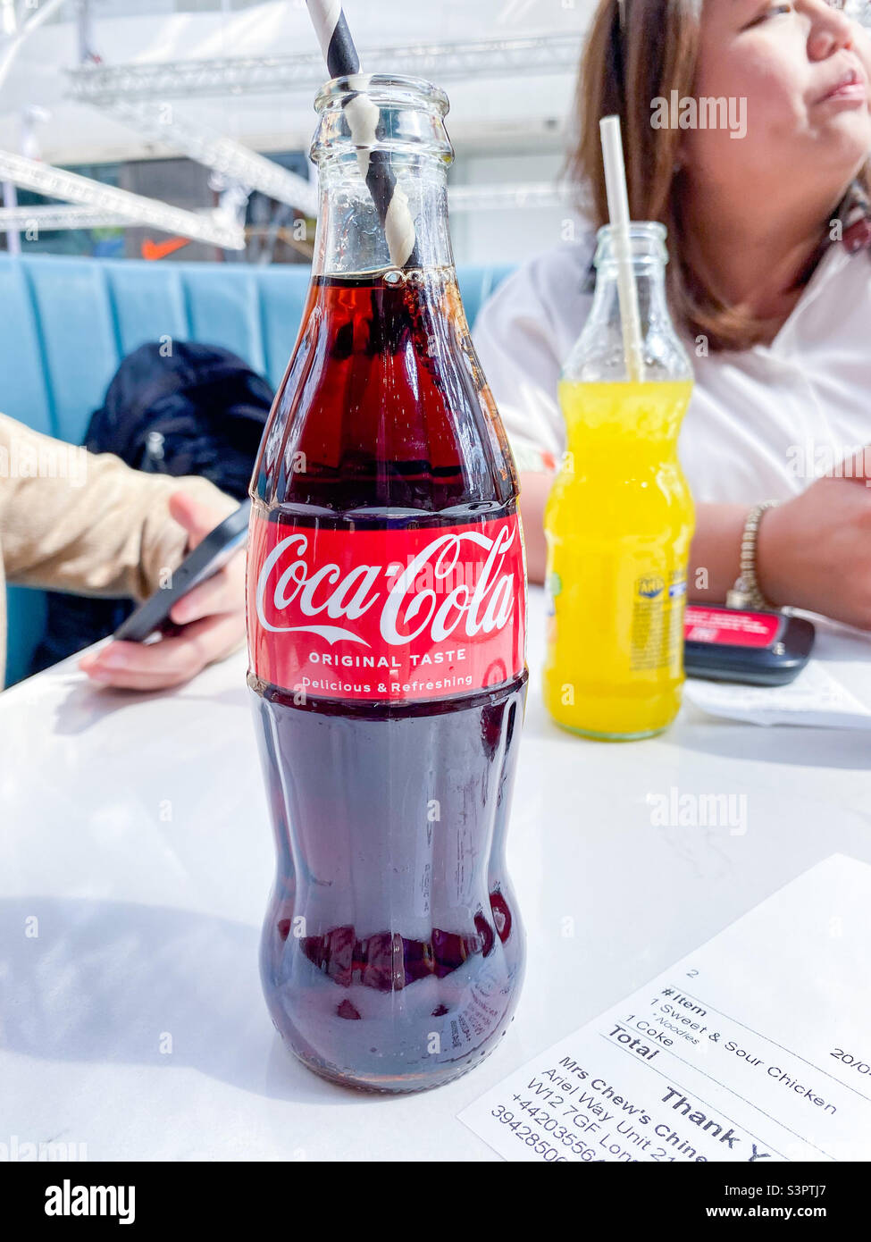 A bottle of Coca-cola on a table in a food court - Smartphone Captured Stock Image