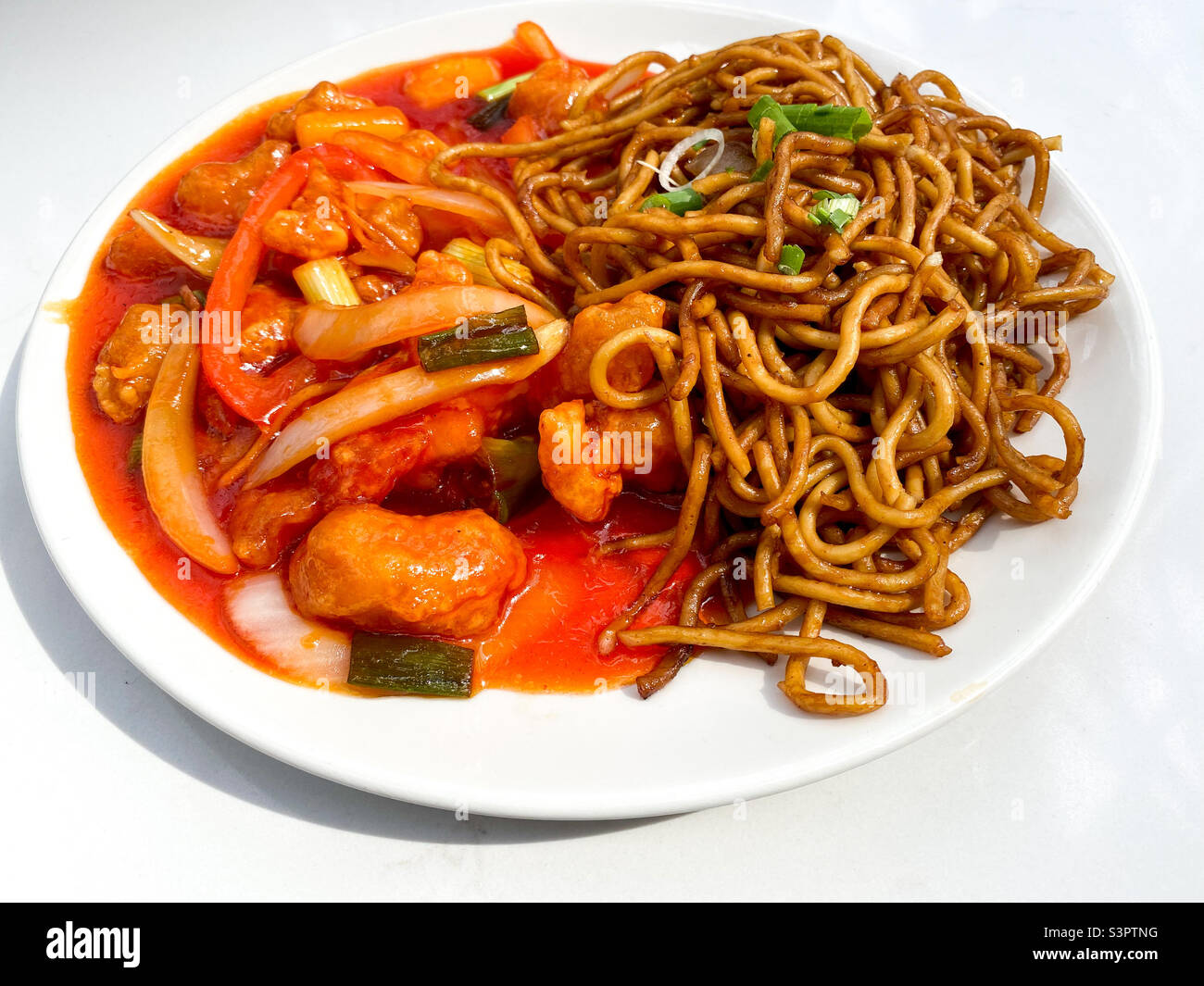 Plate of sweet and sour chicken with wok fried noodles. - Smartphone Captured Stock Image