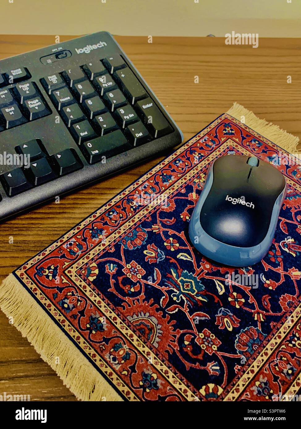 Computer keyboard and Mouse with ethnic fabric mousepad on wooden desk - Smartphone Captured Stock Image
