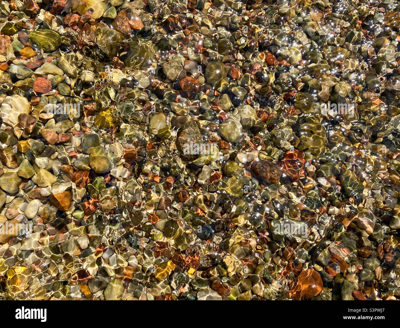 Background of colored river stones or pebbles under water. Top view. Clean and clear water - Smartphone Captured Stock Image