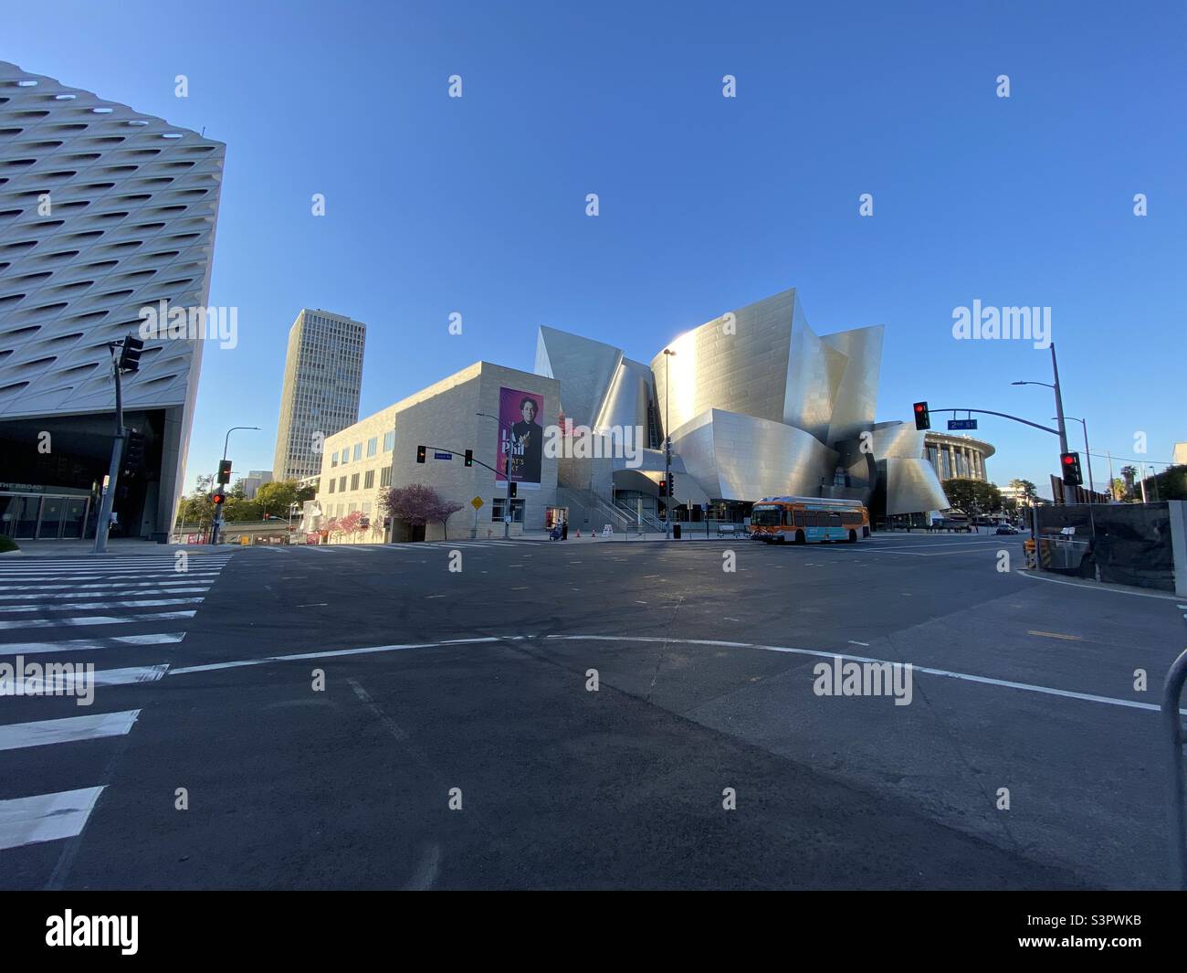 LOS ANGELES, CA, MAR 2021: orange LA Metro bus passes in front of the Walt Disney Concert Hall, designed by Frank Gehry and home to the LA Philharmonic in Downtown Stock Photo