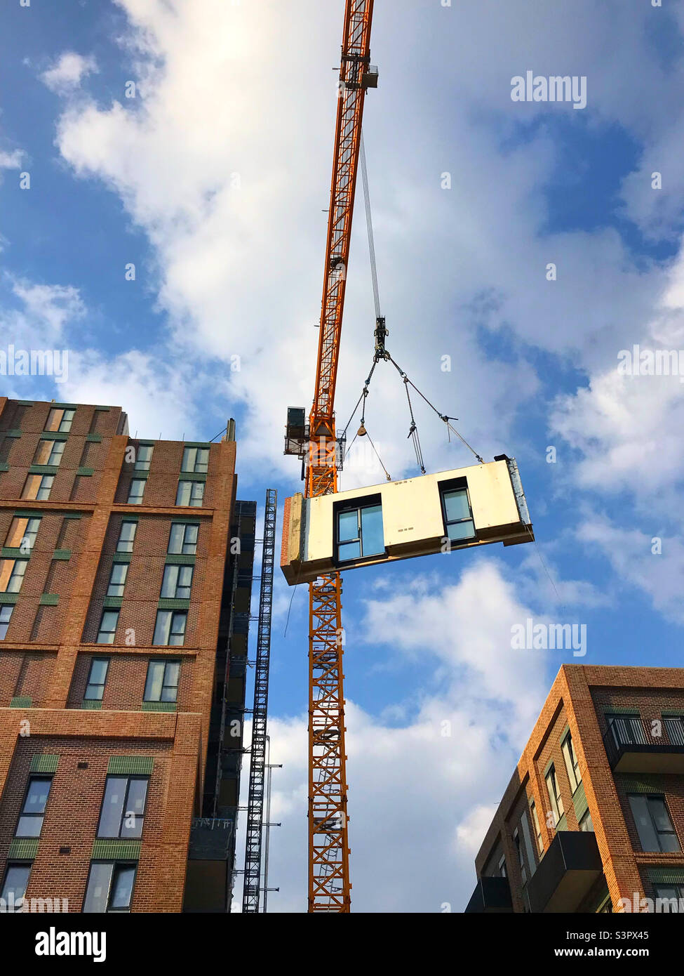 A prefabricated piece of a building being lifted into place by a crane Stock Photo