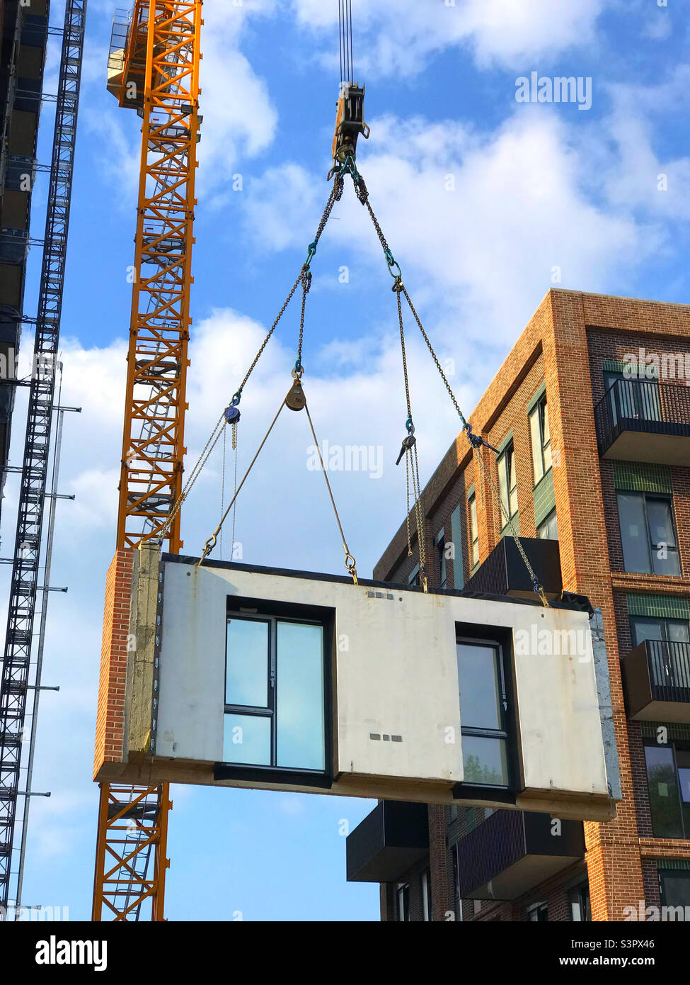 A prefabricated piece of a new building being lifted into place by a crane Stock Photo