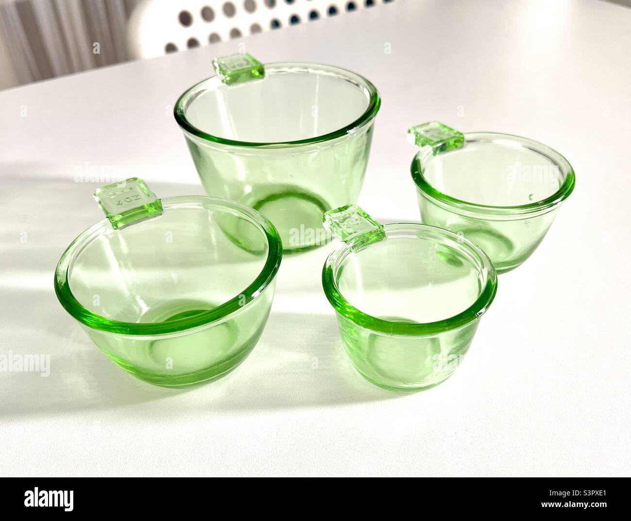 https://c8.alamy.com/comp/S3PXE1/four-neon-green-measuring-cups-on-white-table-depression-style-vintage-glass-bright-see-through-S3PXE1.jpg