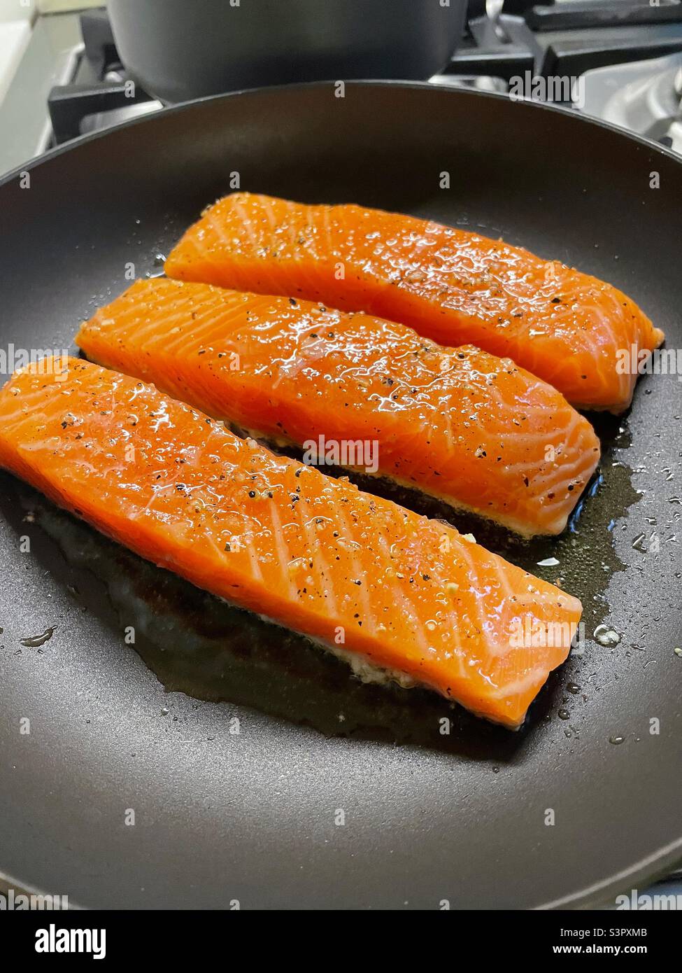 Three fresh salmon fillets frying in a skillet 2022,USA - Smartphone Captured Stock Image