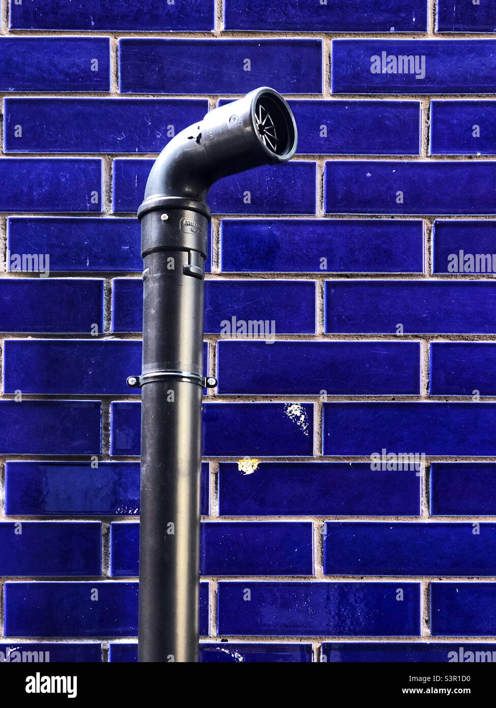 Ventilation pipe on an external blue tile wall Stock Photo