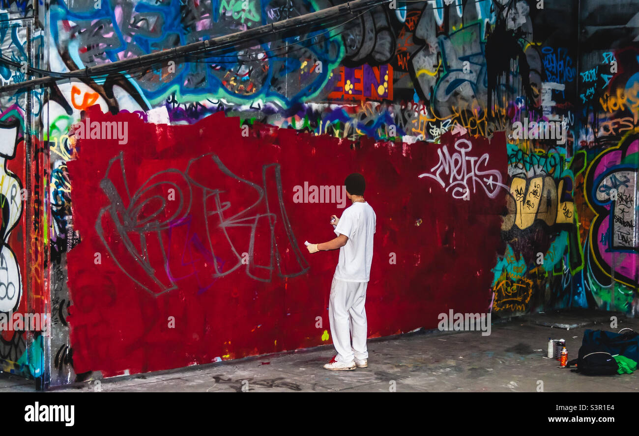 A young street artist dressed in all white begins starting a new piece at the Southbank skate park in London, 2009 - Smartphone Captured Stock Image
