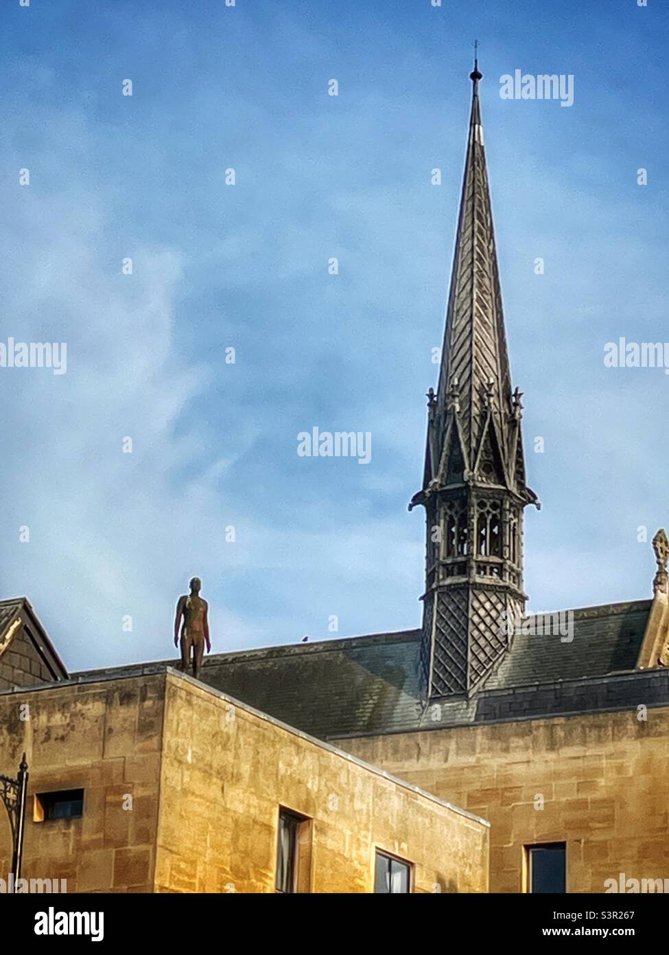 An Antony Gormley sculpture on the roof of Exeter College’s Thomas Wood building, Oxford, UK. Stock Photo