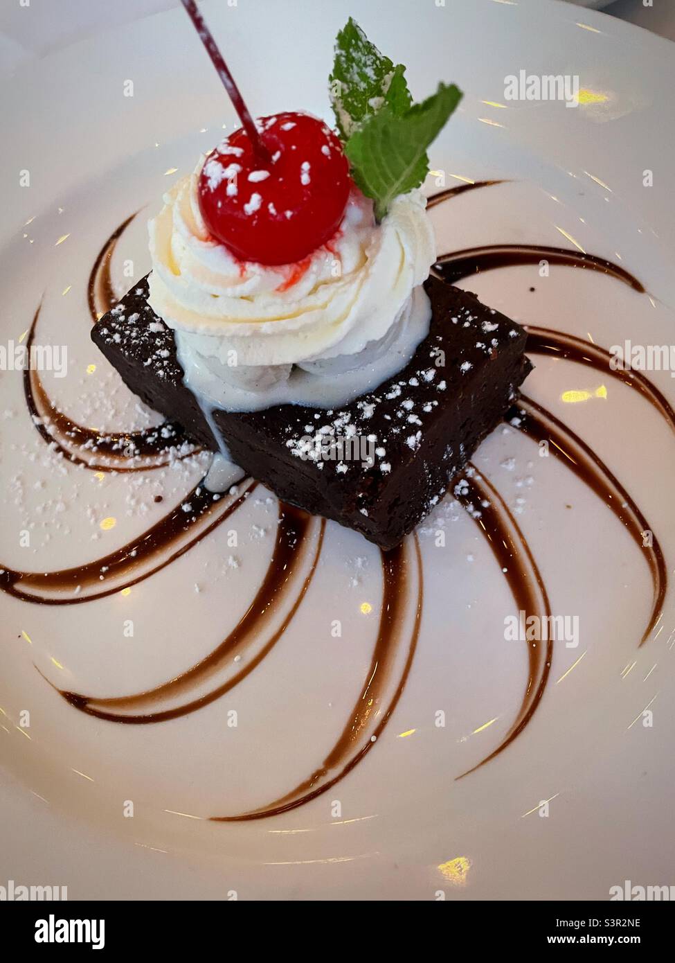 Fancy dessert presentation of a chocolate brownie with ice cream and a