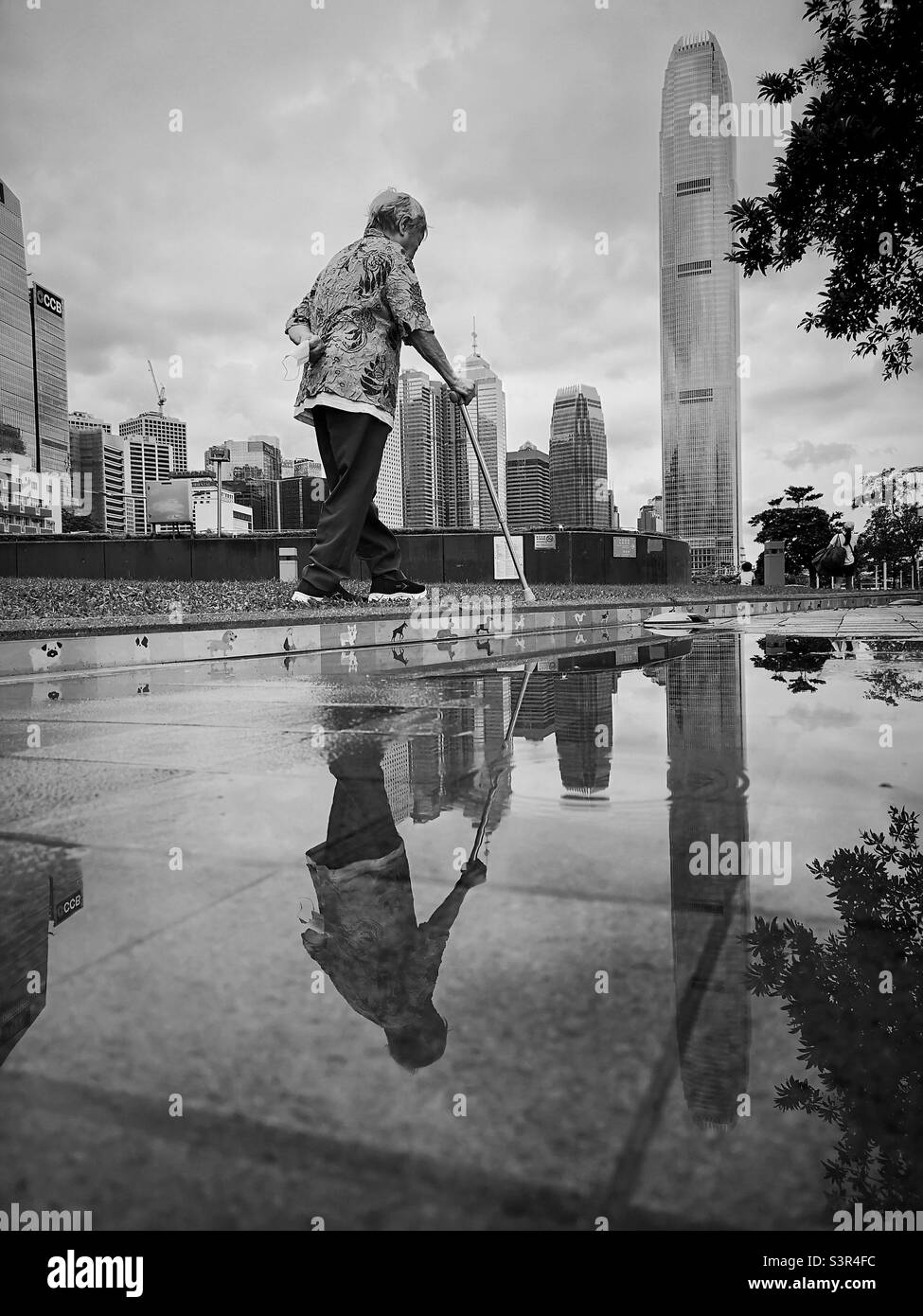 Reflection of old lady in a puddle. Stock Photo