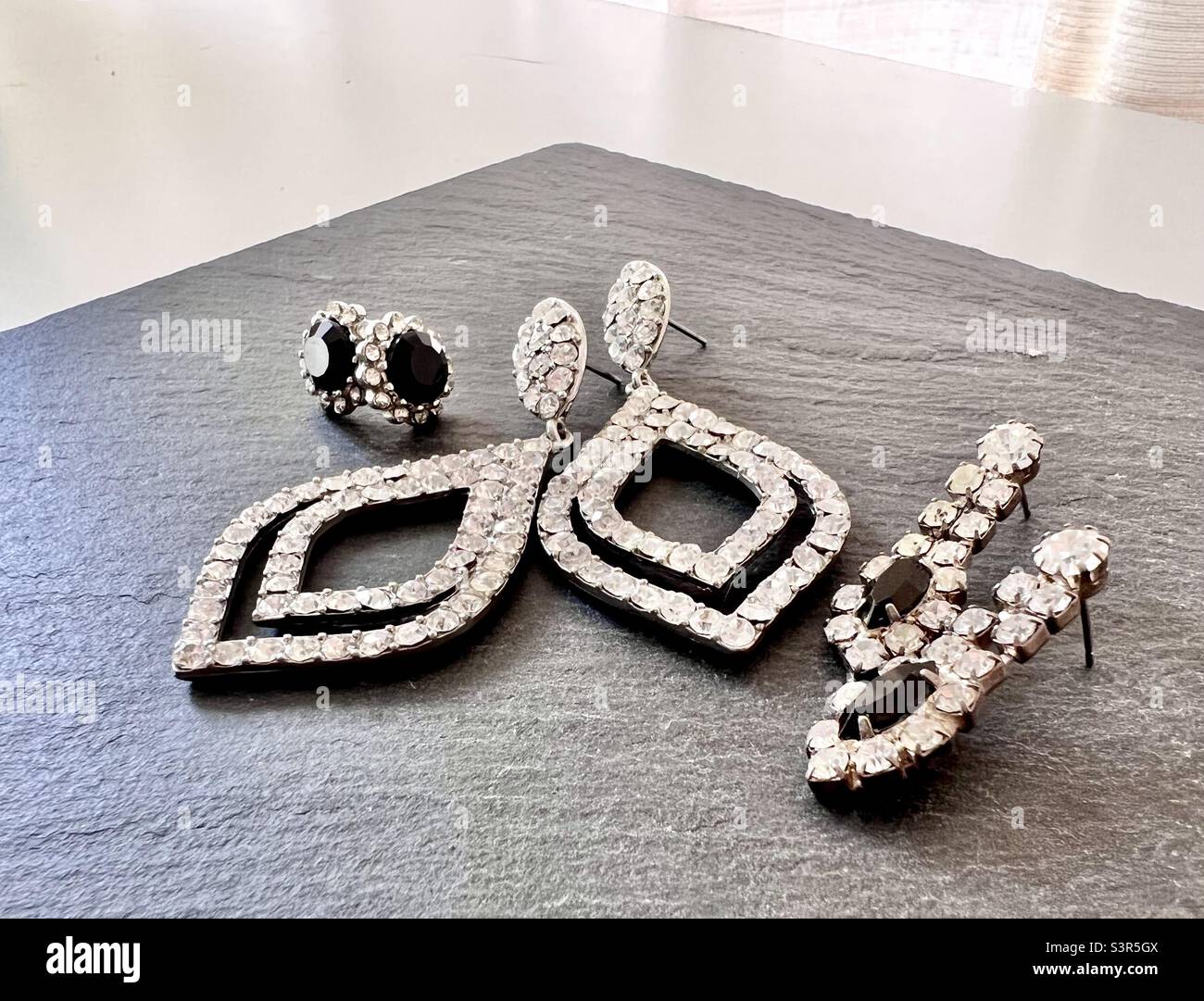 Still life photography of costume jewelry, earrings displayed on gray slate with white background Stock Photo