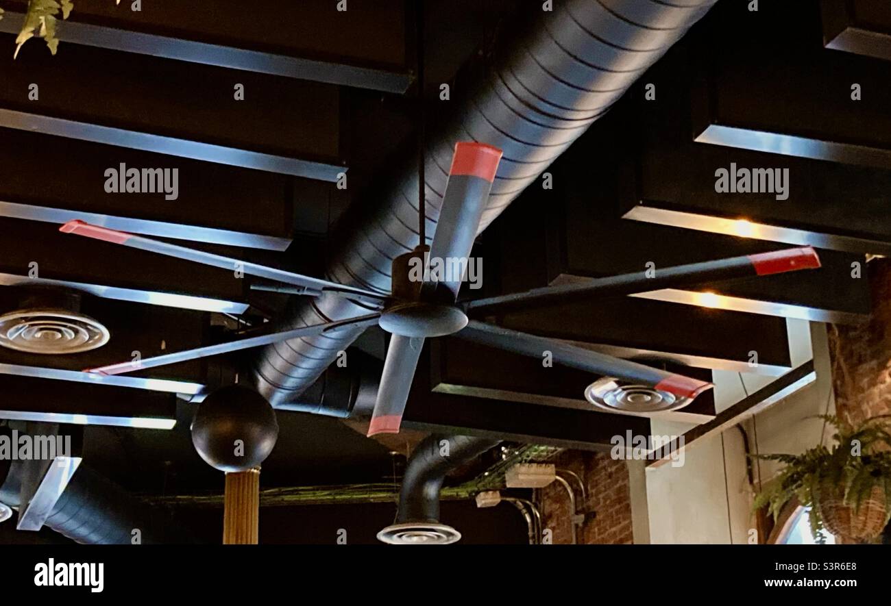 Static black with red tips propellor ceiling fan for cooling in a restaurant in Madrid Spain - Smartphone Captured Stock Image