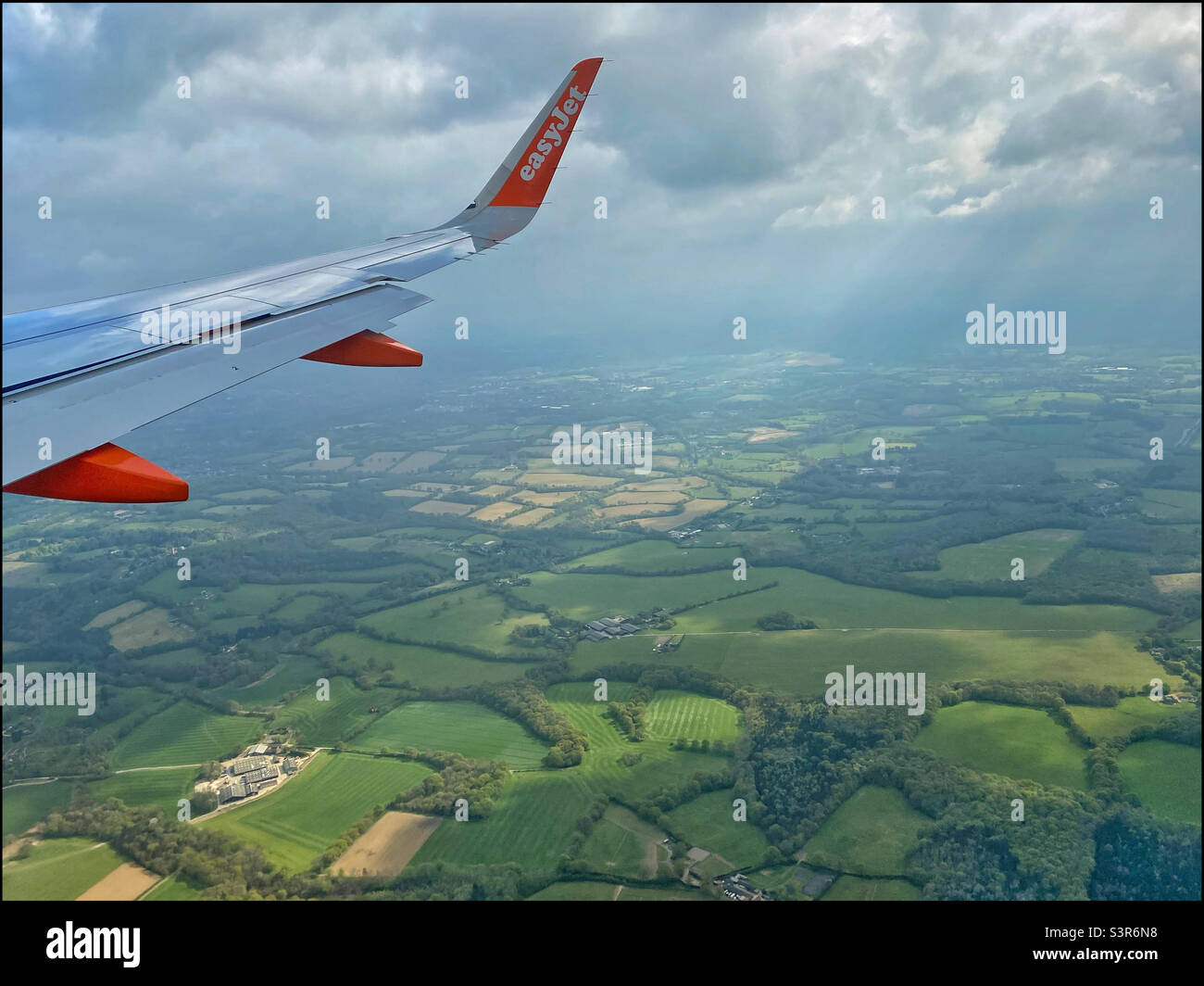 An easyJet Airbus aircraft flies over the south of England as it approaches Gatwick Airport (LGW). It is springtime so the landscape is starting to turn green. Photo ©️ COLIN HOSKINS. - Smartphone Captured Stock Image