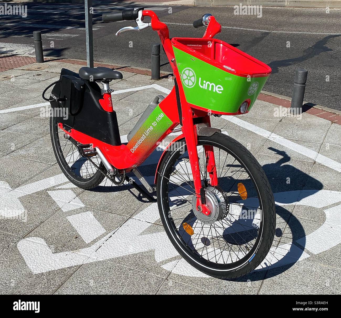 A Lime e-bike is parked in a designated space ready for the next member to use it. Electric bikes are becoming more and more popular for short journeys as an alternative to cars. Stock Photo